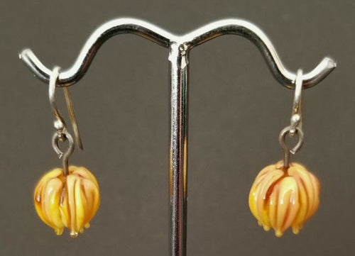 Miniature yellow and light orange glass earrings with sterling silver ear wires.  They are in a delicate blossom shape and look like dew may drip from them at any moment.  The glass blossoms measure approx. one half inch.