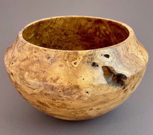 A beautiful turned bowl made of madrone burl.  It is a a mix of honey brown shades.  It reminds us of a shape used in Native American bowls - it is wider in the center and narrowed at top and bottom with a wide opening at top.  There are a few knot holes in one side of it, reflecting the naturalness of the wood.